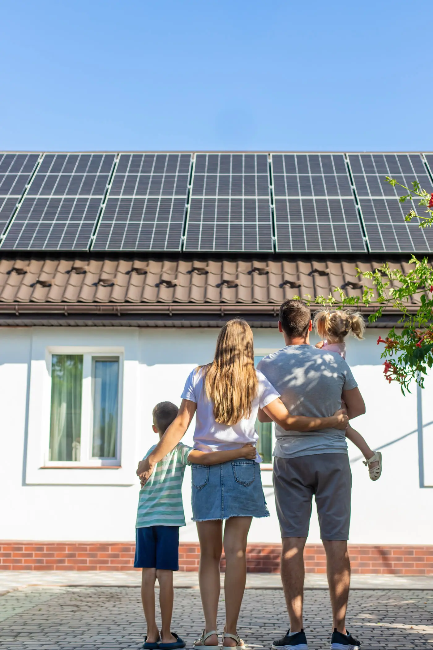 Gezin kijkt naar hun woning met zonnepanelen op het dak